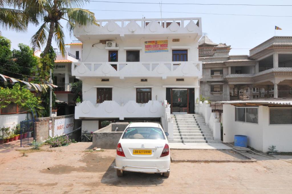 une voiture blanche garée devant un bâtiment dans l'établissement Rama Guest House, à Bodh Gaya