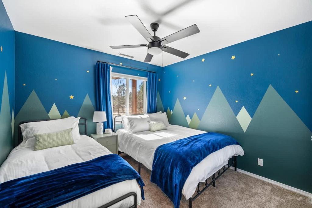 a blue bedroom with two beds and a ceiling fan at Mountain Cabin with Hot Tub in Flagstaff