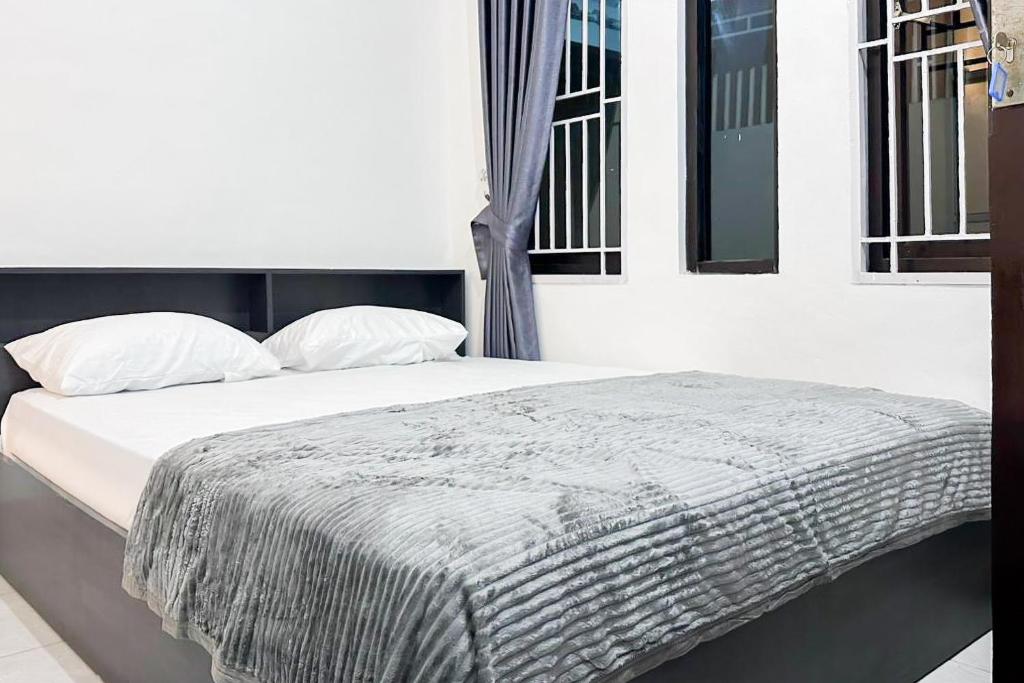 Una cama con una manta encima en un dormitorio. en RedDoorz near Bandara Depati Amir, 