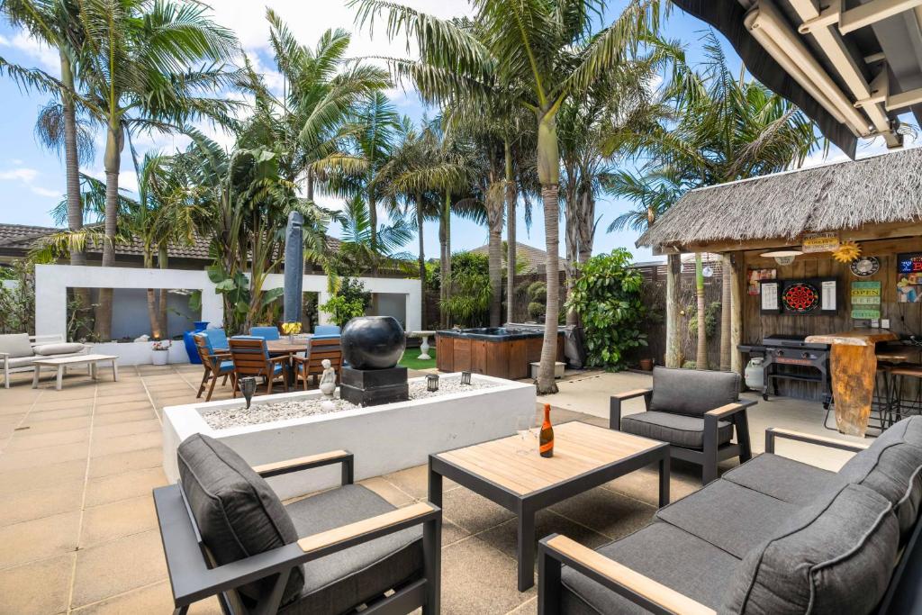 a patio with furniture and a fountain and palm trees at Beach Escape Papamoa in Papamoa