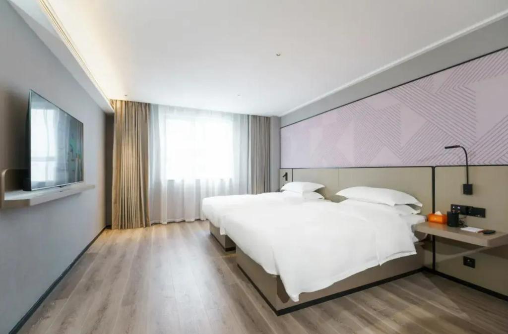 Un dormitorio con una cama blanca grande y una ventana en Parkman Hotel Guangzhou Pazhou Convention and Exhibition Center Luntou Branch, en Guangzhou