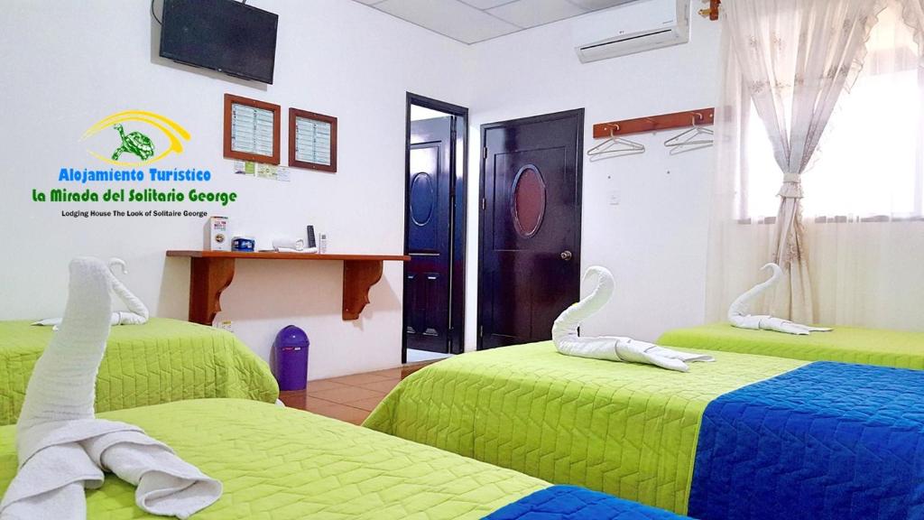 Habitación con 2 camas con sábanas verdes en Hostal La Mirada del Solitario George, en Puerto Ayora