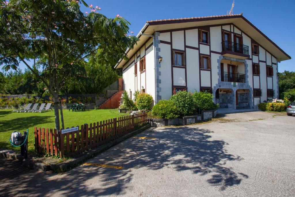 een groot wit gebouw met een hek ervoor bij Casa Rural Zelaieta BerriBi in Itziar