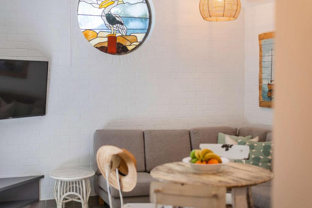 Bayshore Bungalow 5 - Oceanstays في خليج بايرون: غرفة معيشة مع أريكة وطاولة مع وعاء من الفاكهة