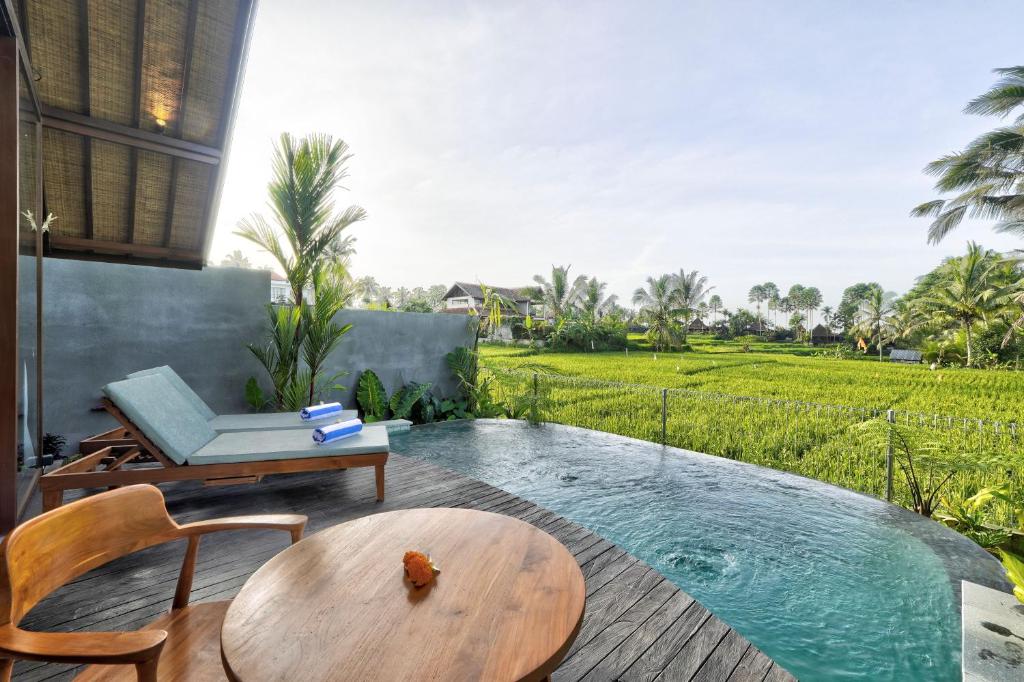 a patio with a plunge pool and a table and chairs at The Udiana Ubud in Tegalalang