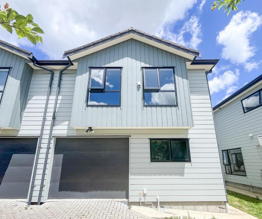 a white house with a garage at Brand-New 5BR Retreat, Space & Serenity by Nature in Auckland