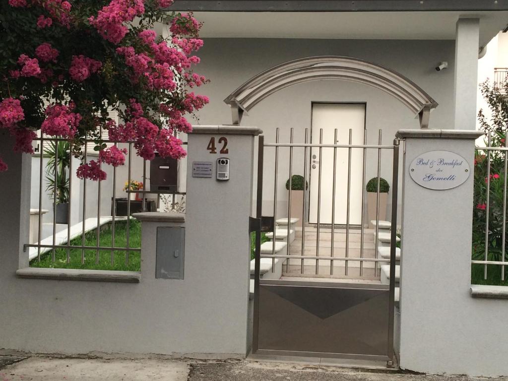 una puerta frente a una casa con flores rosas en B&B dei Gemelli, en Bareggio