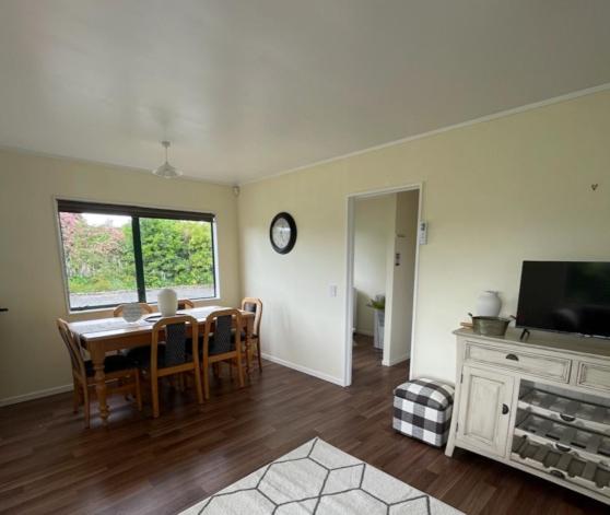 een eetkamer met een tafel, stoelen en een televisie bij Gordonton Greenmeadows Cottage in Taupiri