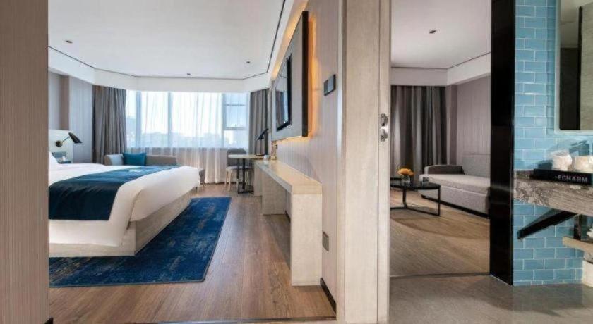 ein Hotelzimmer mit einem Bett und einem Wohnzimmer in der Unterkunft Echarm Hotel Shenzhen International Exhibition Center Fuyong in Fenghuangwei