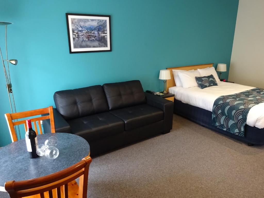 a living room with a couch and a bed and a table at Victoria Lodge Motor Inn & Apartments in Portland