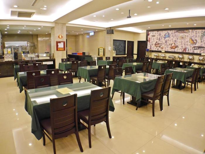 a restaurant with green tables and chairs and a buffet at Chong Yu Hotel in Taoyuan