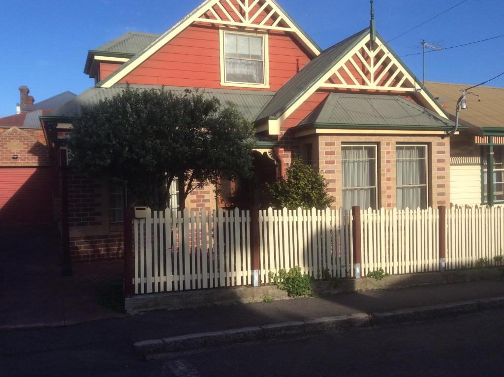a red house with a white picket fence at City townhouse walking distance to city in Launceston