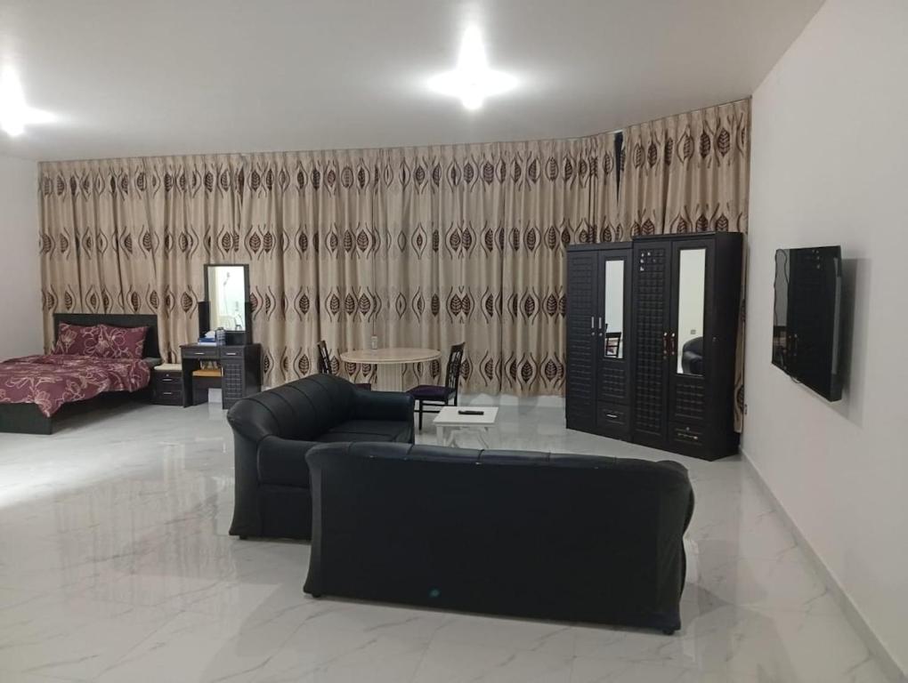 Big Studio In Abu Dhabi Corniche في أبوظبي: غرفة معيشة مع أريكة وتلفزيون