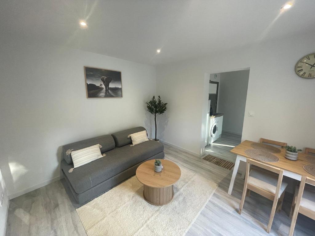 ein Wohnzimmer mit Sofa und Tisch in der Unterkunft Appartement Japandi proche Thermes Cocon Zen Contrexéville in Contrexéville