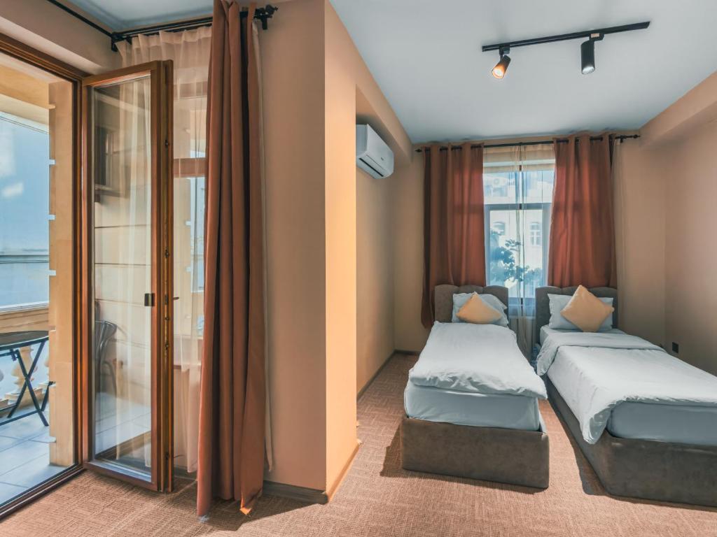 Una habitación de hotel con dos camas y balcón. en Dastan Boutique Hotel Baku, en Baku