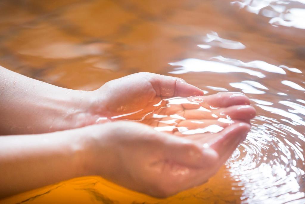 a person washing their hands in the water at Kanazawa Hakuchoro Hotel Sanraku -Natural Hot Spring- in Kanazawa