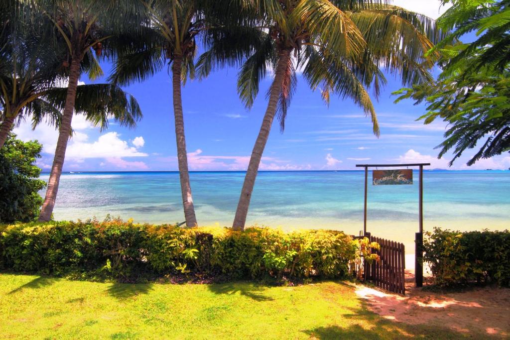 a view of the ocean from a beach with palm trees at Coconut Grove Beachfront Cottages in Matei