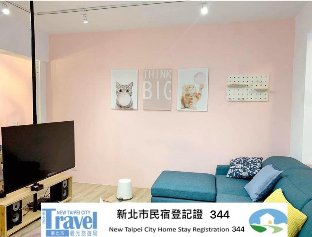 a living room with a blue couch and a flat screen tv at 李家出走民宿 in Sanzhi