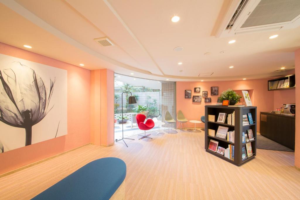 Tokyu Stay Meguro Yutenji في طوكيو: غرفة معيشة مع جدران برتقالية ورف كتاب
