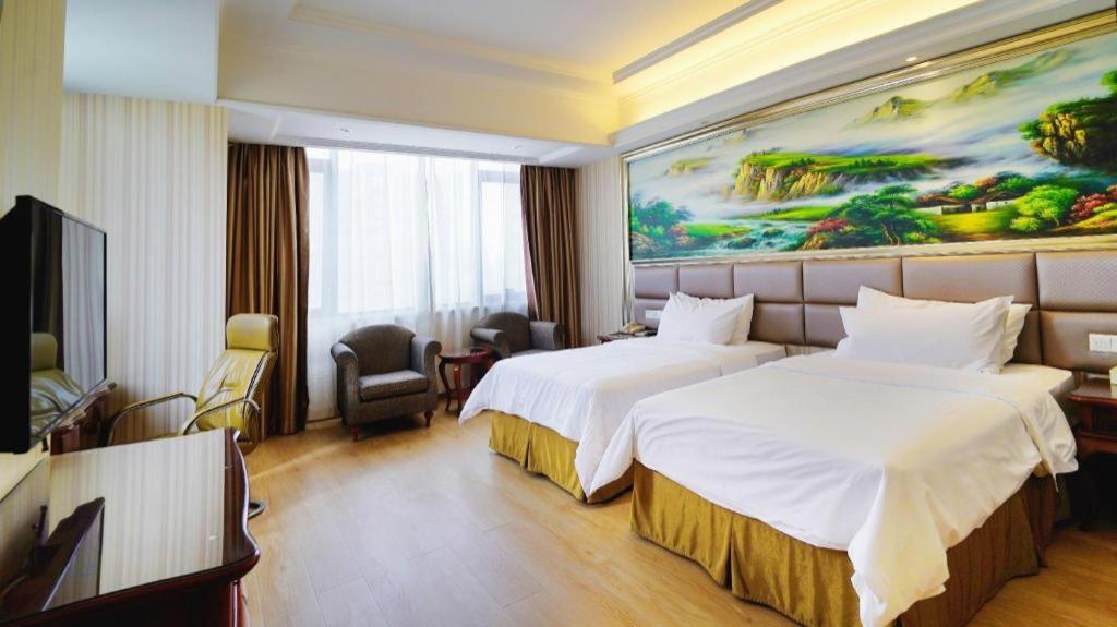 Una habitación de hotel con dos camas y un cuadro en la pared. en Vienna International Shanghai Nanxiang, en Chenjiahang