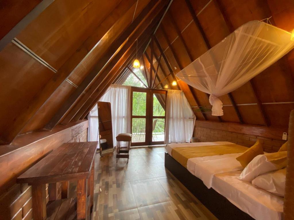 a bedroom with a bed and a table in a attic at Green Forest Cabanas - Ella in Ella