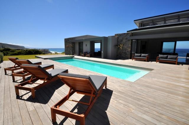 a group of chairs sitting next to a swimming pool at Cliffhanger Estate in Keurboomstrand