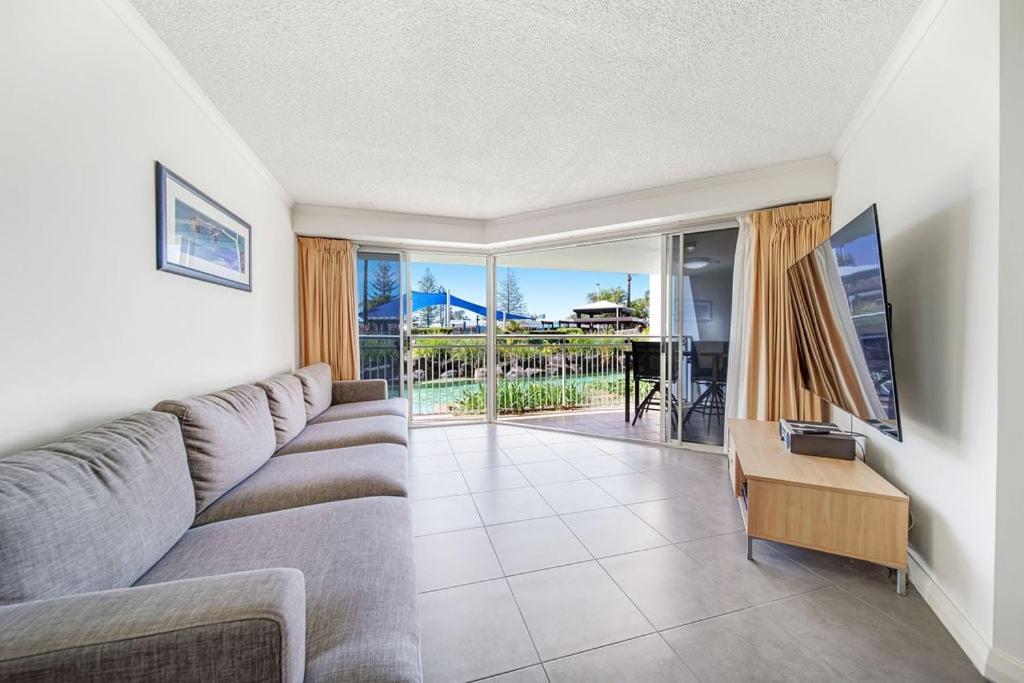 Una sala de estar con un sofá y una puerta corrediza de vidrio. en Poolside Escape at Alexandra Headland, en Alexandra Headland