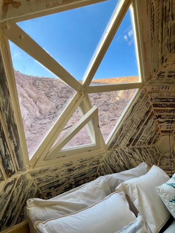 a bed in a room with a large window at Mannam desert dome in Dahab