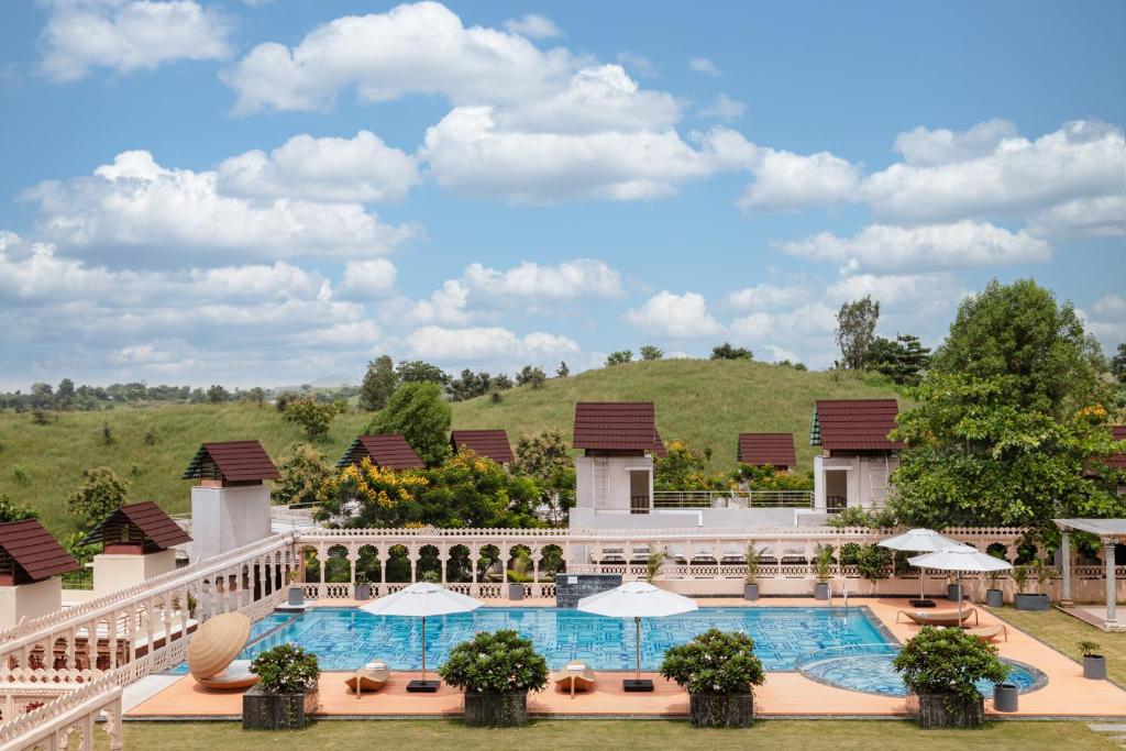 a view of the pool at a resort with a hill in the background at WelcomHeritage Akashganga Heritage Hills Resort & Spa 