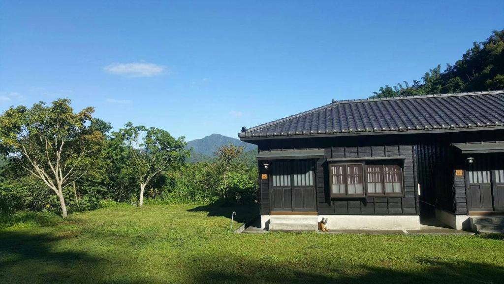 une petite maison avec un chien assis devant elle dans l'établissement Sun Moon Home, à Yuchi