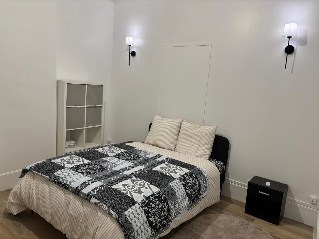 una camera con un letto con una trapunta in bianco e nero di Super appartement a Malesherbes