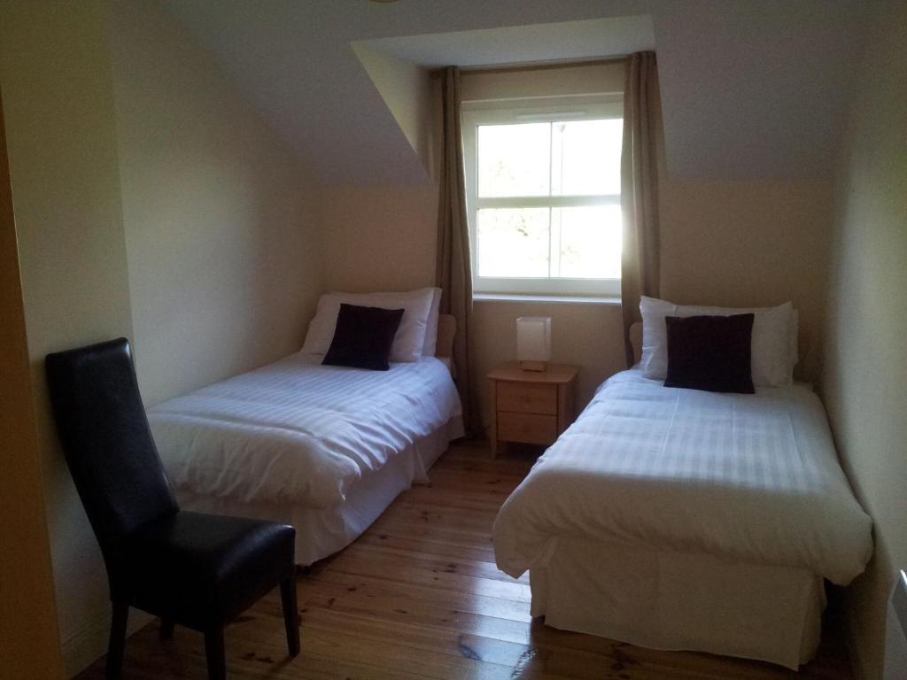 1 dormitorio con 2 camas, silla y ventana en 15 Sheen View Kenmare Co Kerry en Kenmare