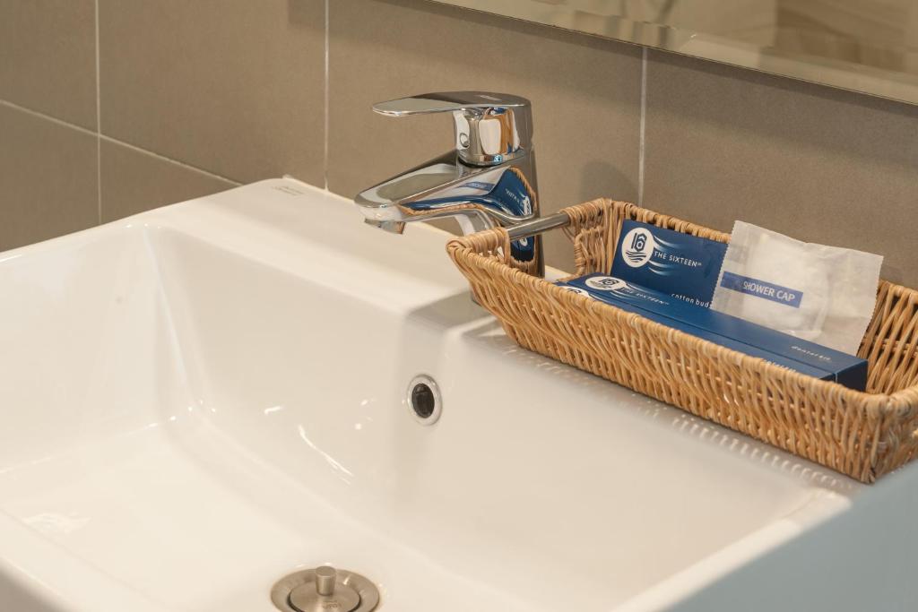 a bathroom sink with a basket of toiletries on it at The Sixteenth Naiyang Beach Hotel SHA Plus in Nai Yang Beach