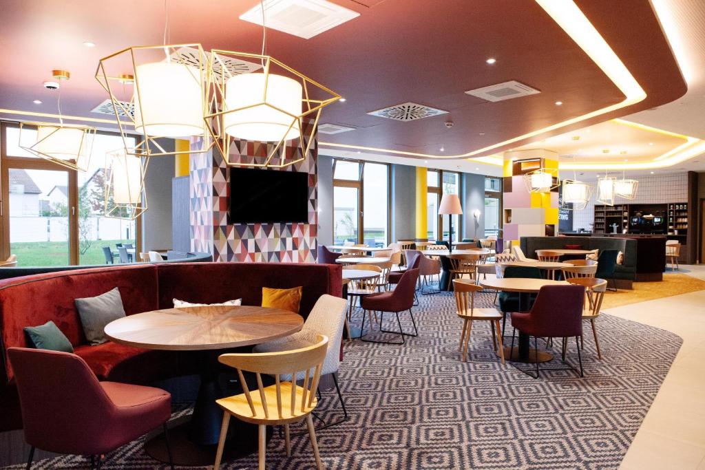 a restaurant with tables and chairs and a tv at Hampton By Hilton Stuttgart Airport in Filderstadt