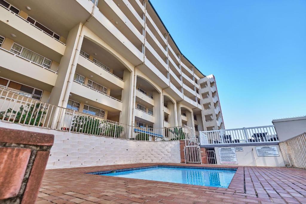 a building with a swimming pool in front of a building at 204 L'escalier Cabanas- Beach front paradise in Amanzimtoti