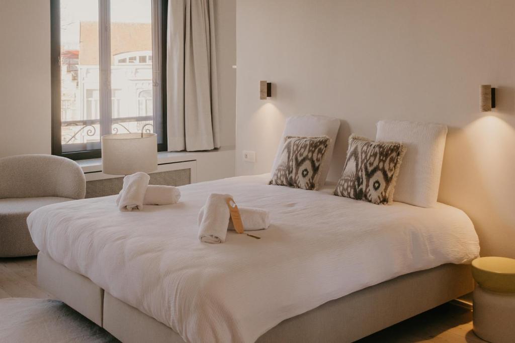 a bedroom with a large white bed with towels on it at Isidore in Bruges