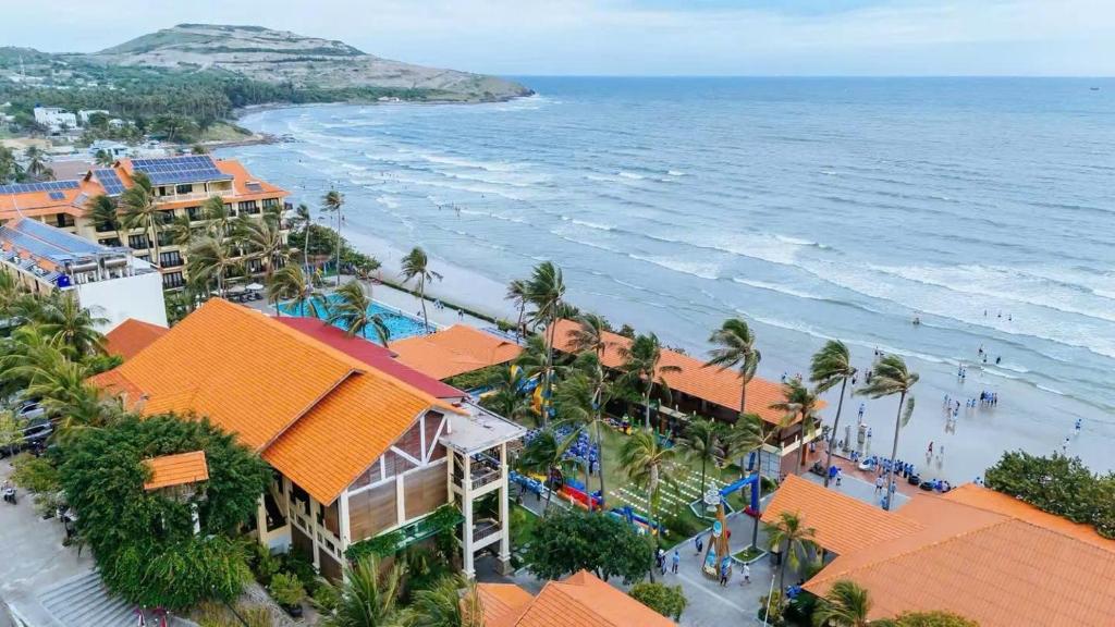 z anteny widok na plażę z palmami i budynkami w obiekcie Hon Rom Central Beach Resort w mieście Mui Ne