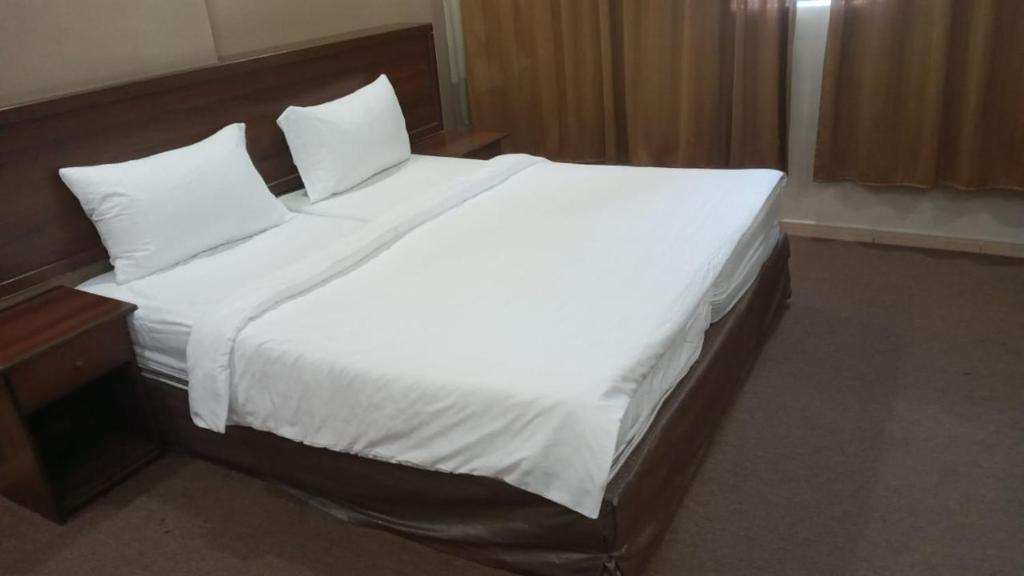 un grand lit blanc dans une chambre d'hôtel dans l'établissement الرحابة المكية الفندقية, à Al Masfalah