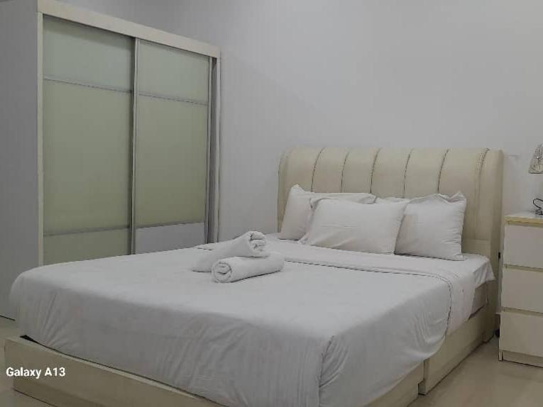 a white bed with a teddy bear sitting on it at Cyberjaya Studio Suite By NSB in Cyberjaya