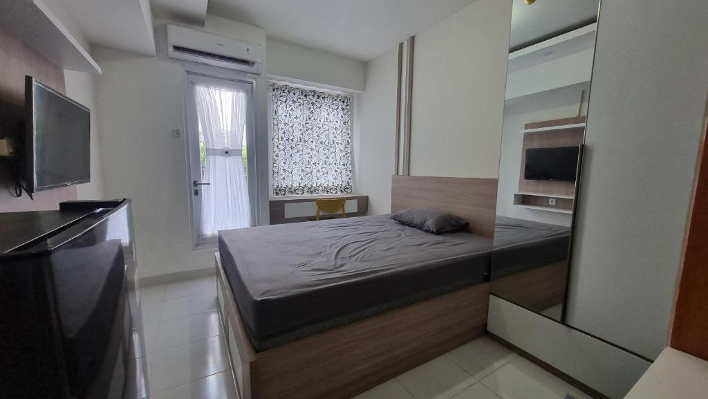 OYO 95052 Cordia Tower في Tjikuda Dua: غرفة نوم صغيرة بها سرير ونافذة