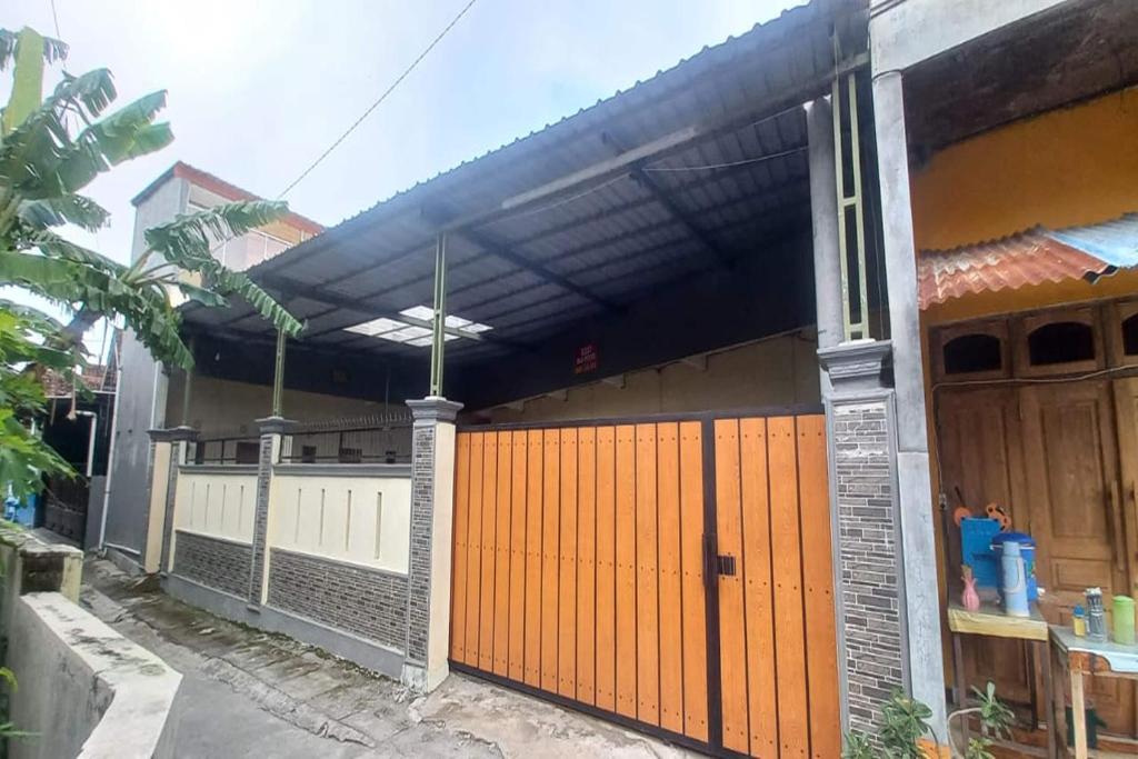 a house with an orange gate and a fence at OYO 95058 Agago Homestay Syariah in Kedungtengkong
