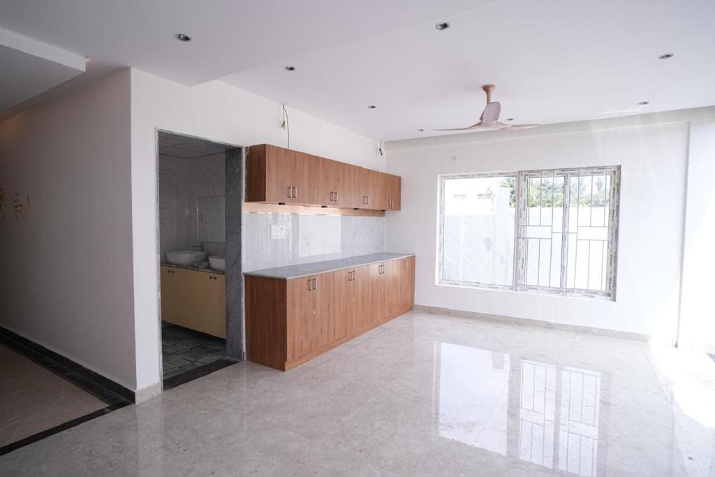 a kitchen with wooden cabinets and a large window at 69th Heaven Hotel in Devanahalli-Bangalore