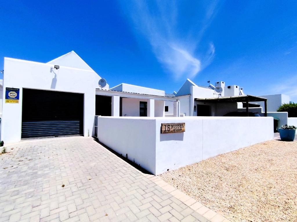 a white house with a garage in front of it at Mosseltjie - Self Catering in Britannia Bay