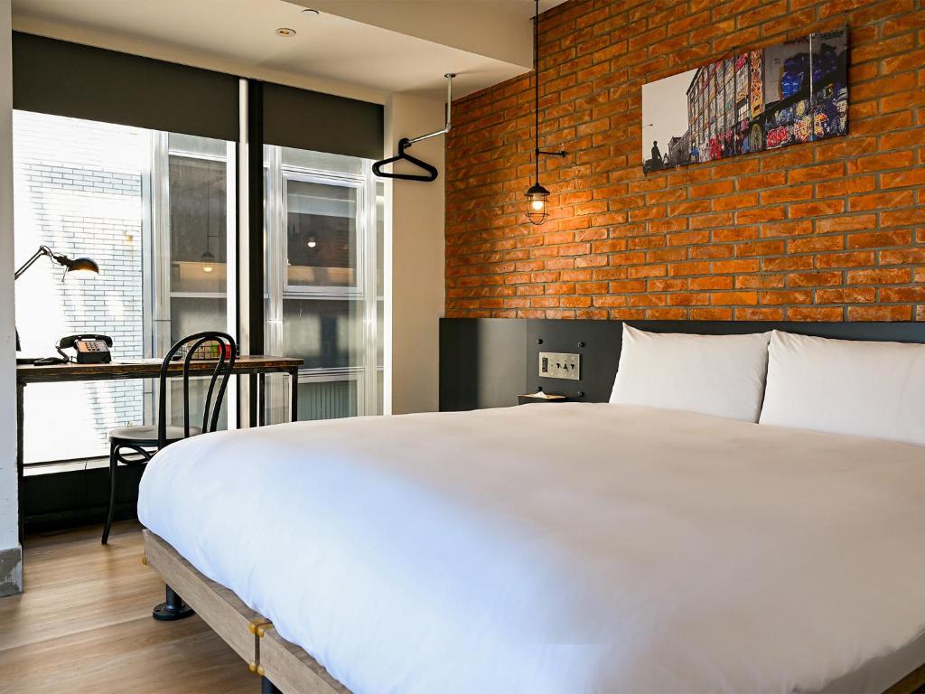 una camera da letto con un letto bianco e un muro di mattoni di CHECK inn Taipei Songjiang a Taipei