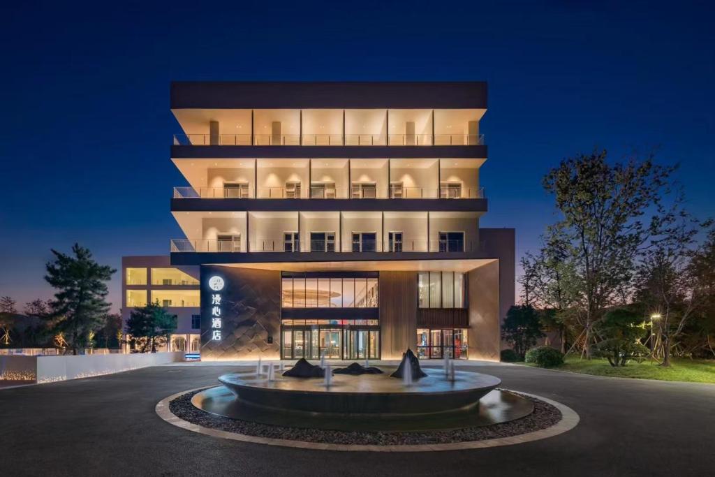 a building with a fountain in front of it at Manxin Hotel, Jingshi Road, Zhangqiu District, Jinan 
