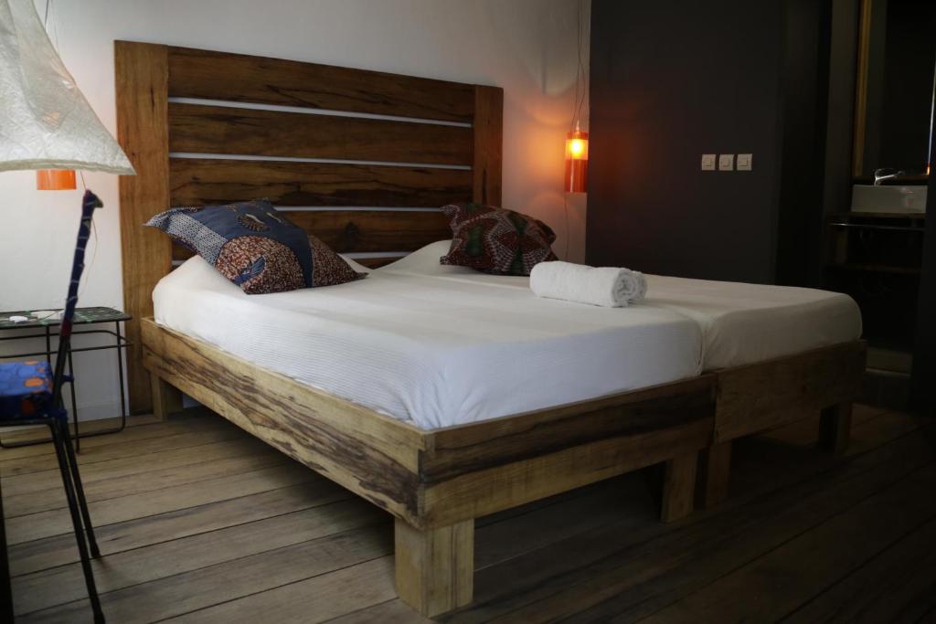 a bedroom with a large bed with a wooden headboard at Siki Hotel in Saint-Louis