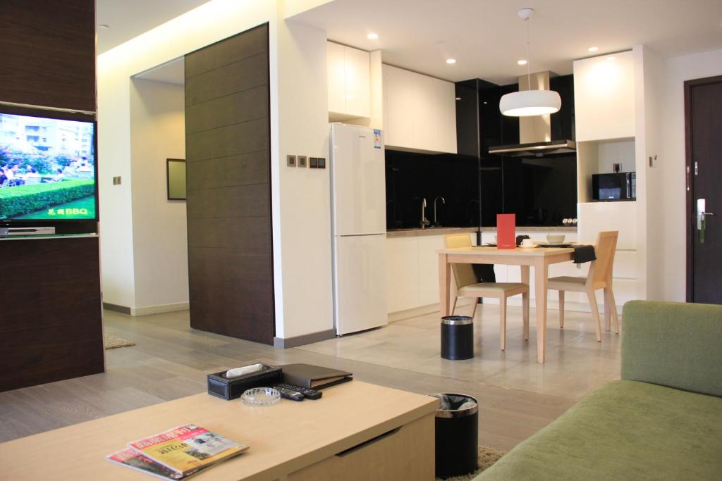 a kitchen and living room with a table and a refrigerator at Green Park Hotel Tianjin in Binhai