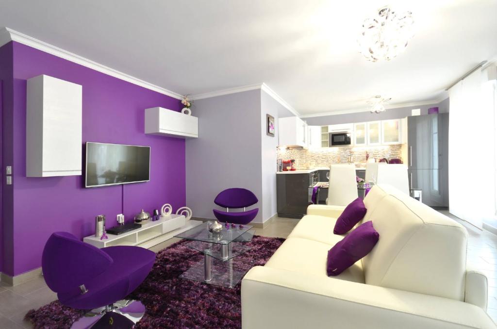 - un salon avec des murs violets et un canapé blanc dans l'établissement Djanea Luxury Apartment - Disneyland Paris, à Serris