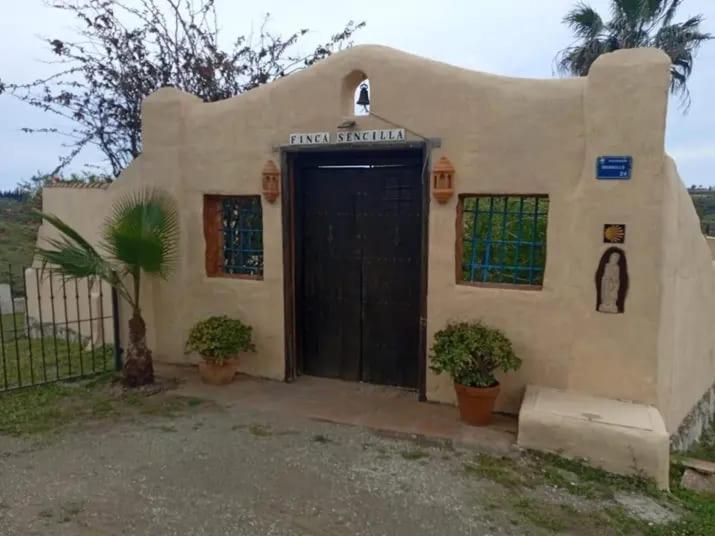 a small house with a black door and two plants at Finca Sencilla in Mijas