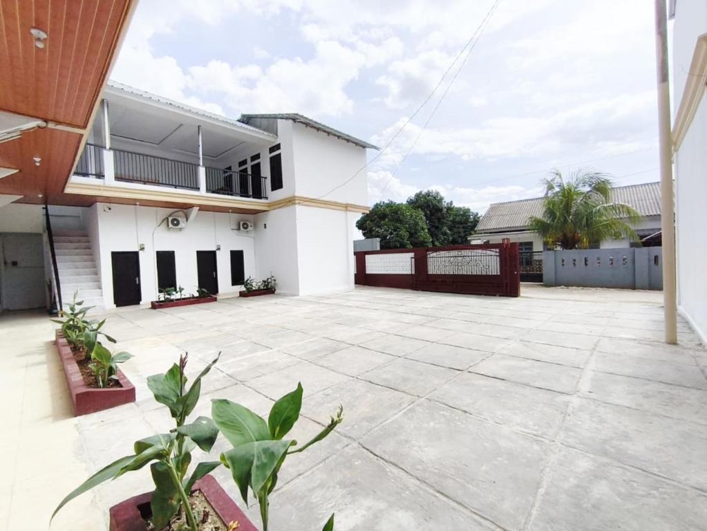 a white house with a courtyard in front of it at HAJIMENA INN Syariah By Hans Management in Hajimana